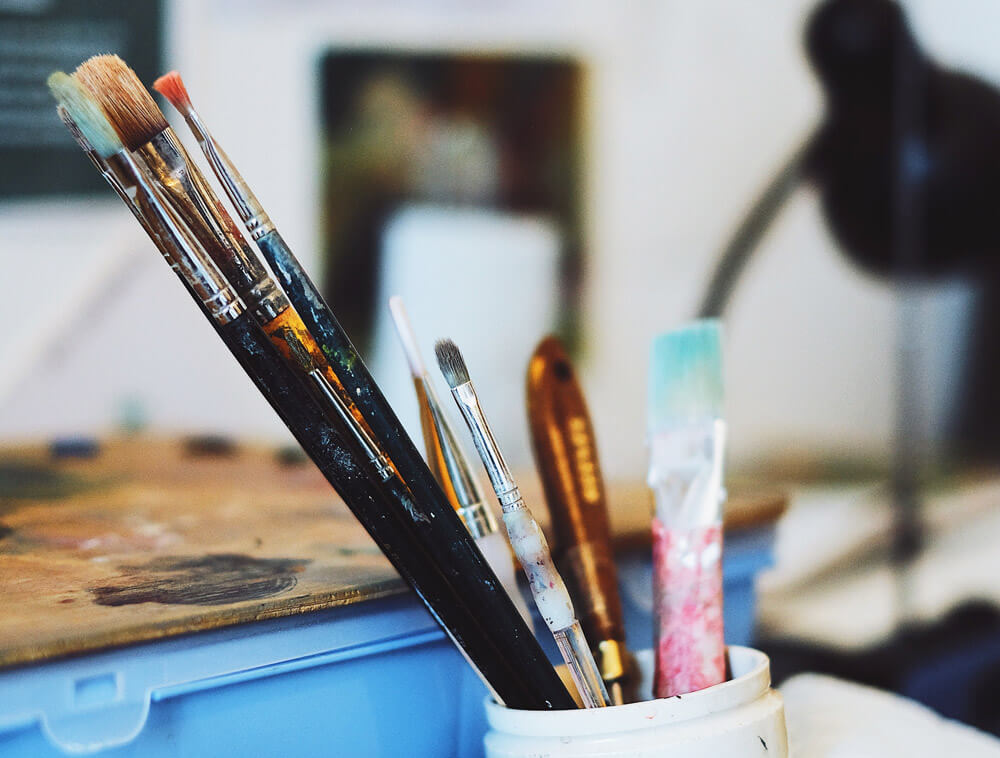 Disorganized artist studio with paintbrushes in an old container