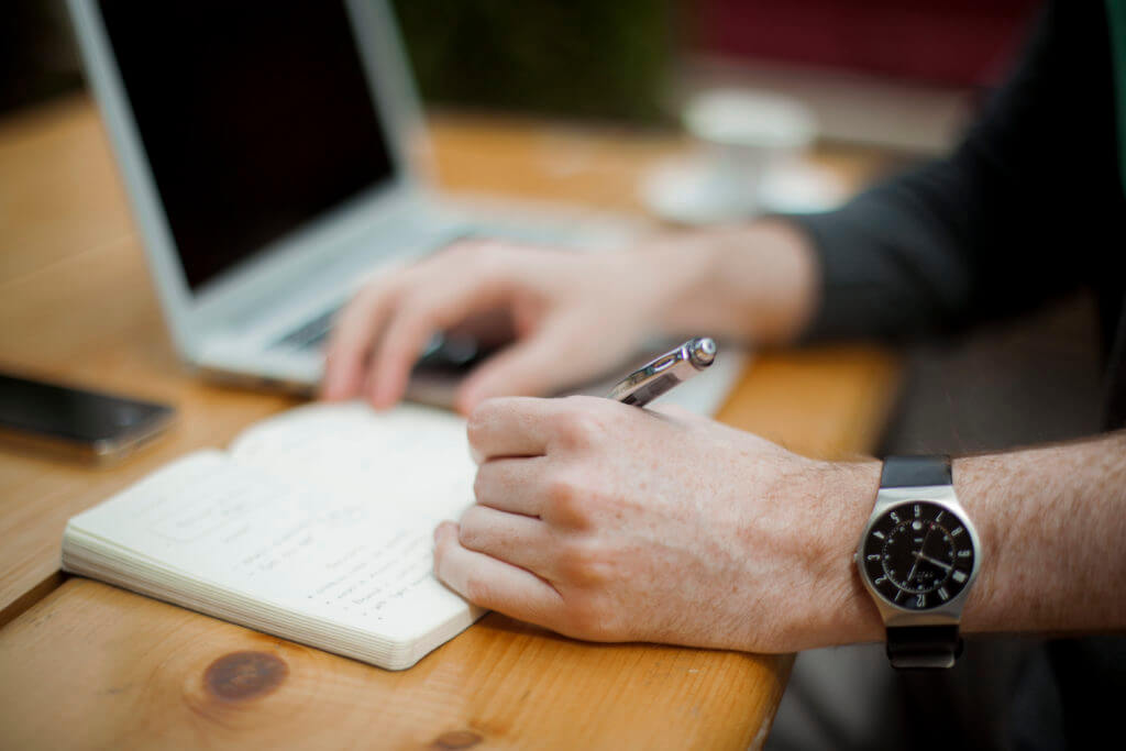 Writing a list of ideas next to a laptop